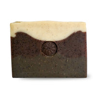 An unwrapped bar of TONIC's Cardamom Coffee Soap ona white background