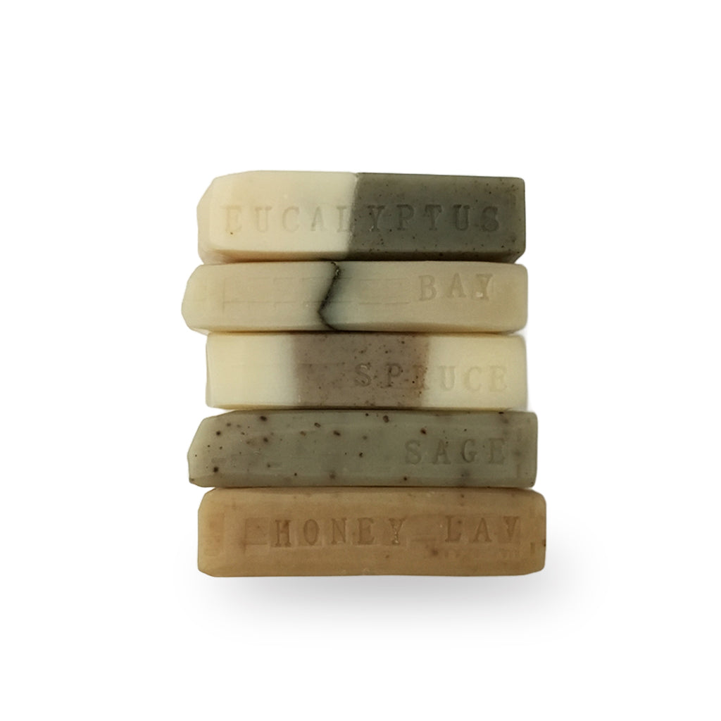A stack of cold process petit bar soaps - eucalyptus, bay laurel, spruce & fir, sage, and honey lavender.