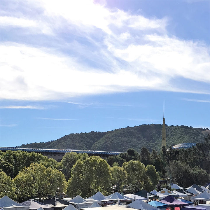 San Rafael Civic Center Spire and Hills under a Blue sky with whispy clouds and mostly white Market tent tops in the foreground