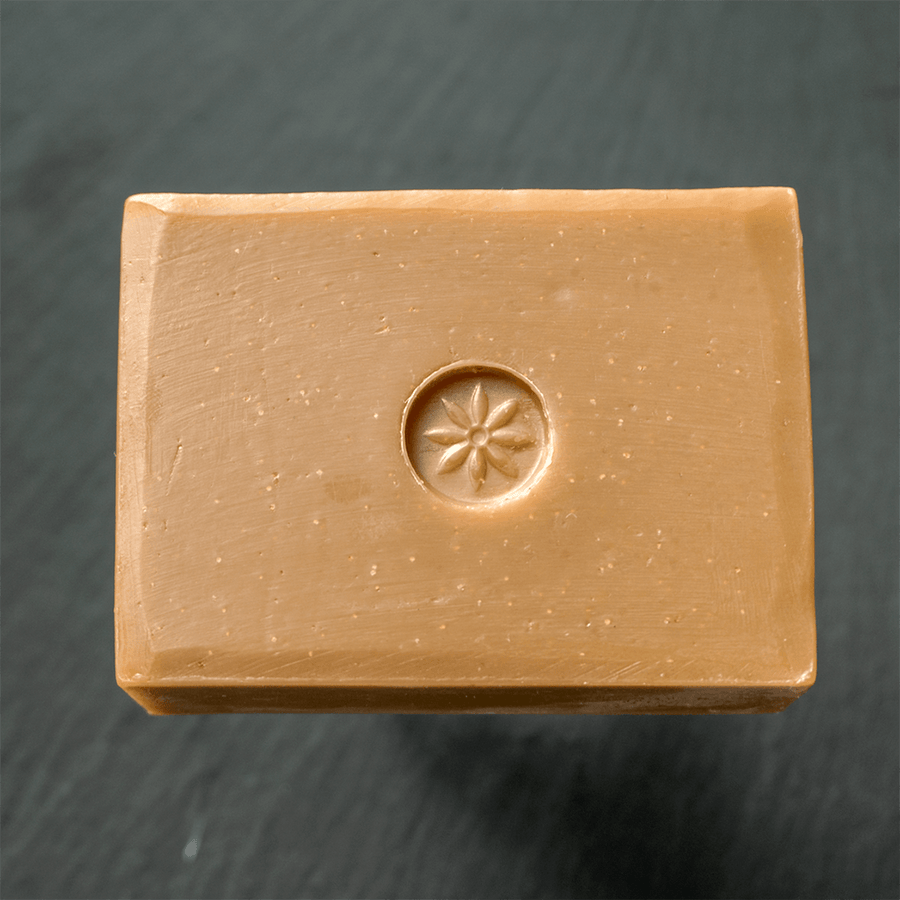 Tonic Naturals Oatmeal Stout Bar Soap unwrapped on a slate background.