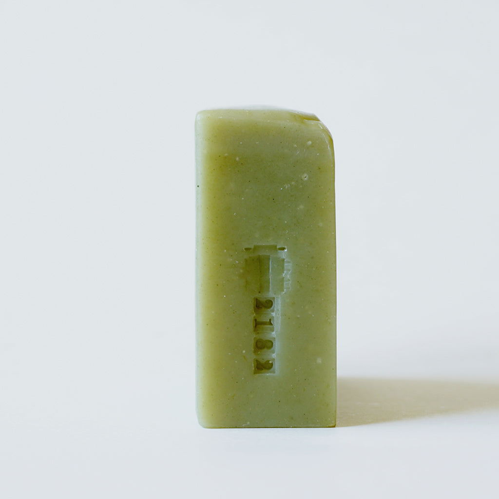 Side view of an unwrapped Avocado bar soap with batch stamp 2182