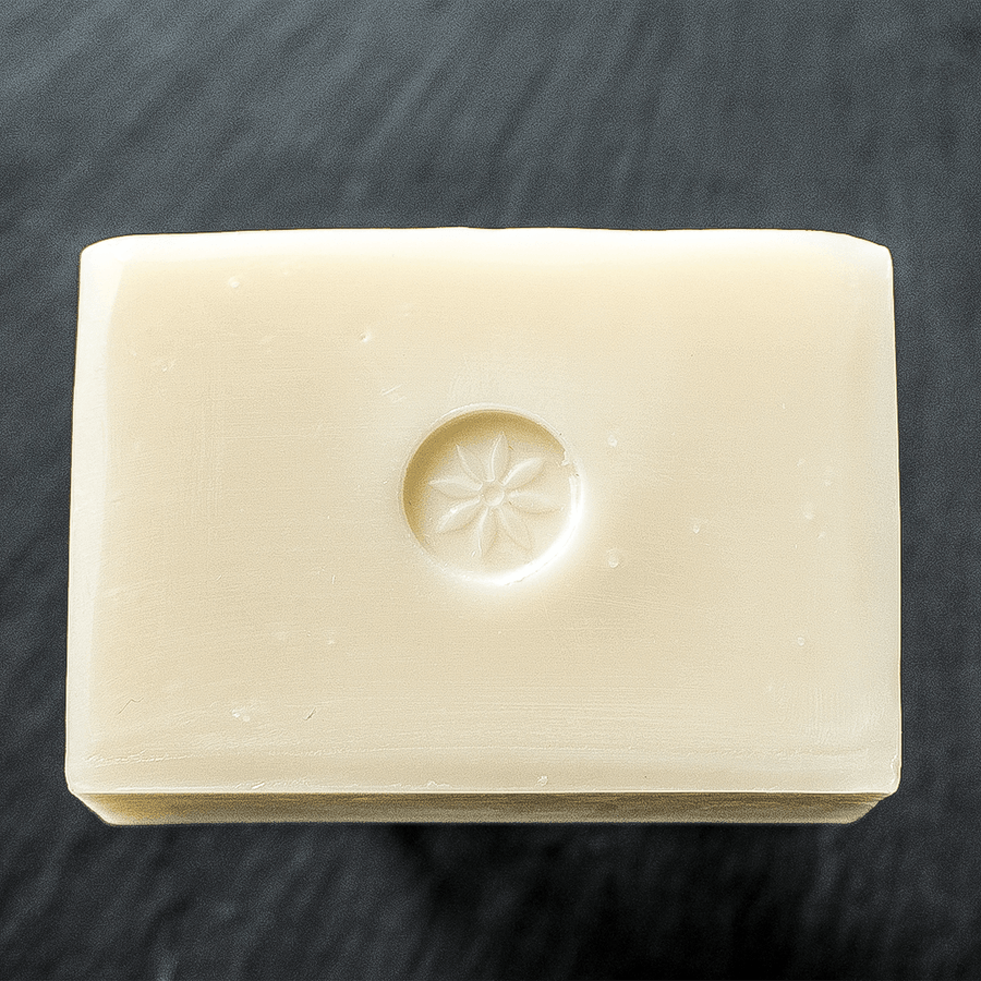 Naked unscented bar soap unwrapped on a black slate background
