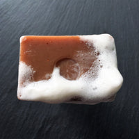 Cedar Sandalwood bar soap with lather on a dark slate background