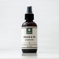 Spruce and Fir Aromatic Essential Oil Room Mist in an amber glass bottle with black pump on an off white background